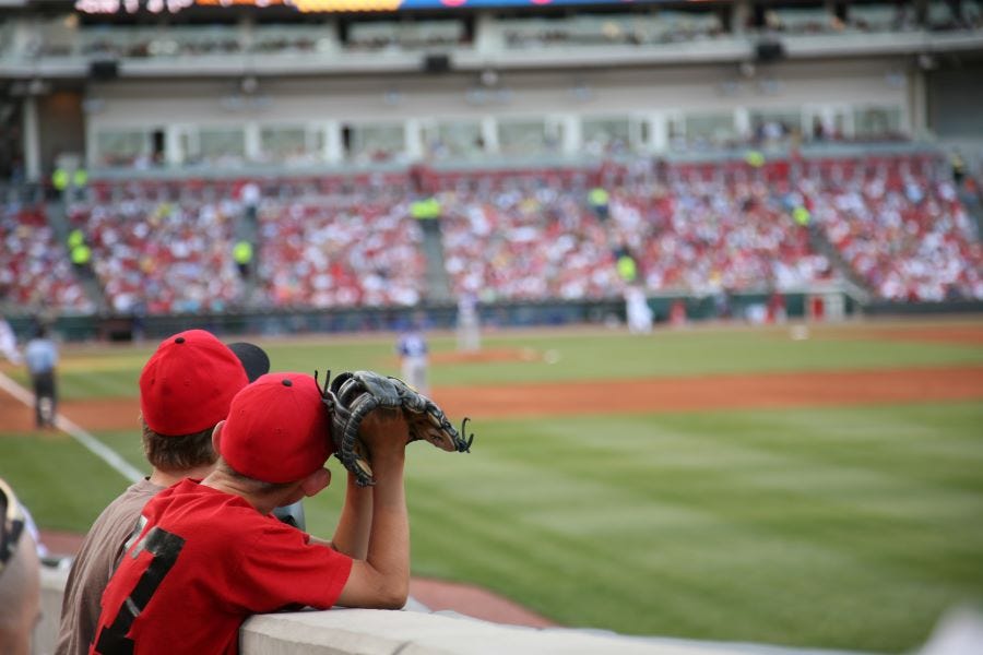 two young boys with catchers mits, leaning over the wall at a baseball stadium, watching the players, a Southwest Florida Labor Day Weekend events